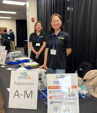 Two students standing at the registration desk for IEEE-FISTS 2024 International Conference for Sustainable Transportation