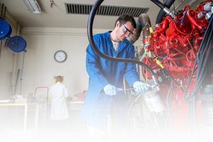 EFR HDD info card  Researcher in a blue lab coat working with engine testing equipment at CE-CERT.