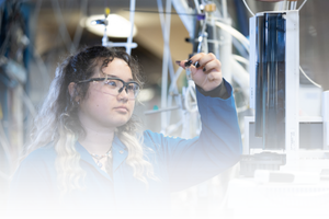 Atmospheric Chemistry and Air Quality image Student in a blue lab coat examining a scientific sample inside a research laboratory at UC Riverside.