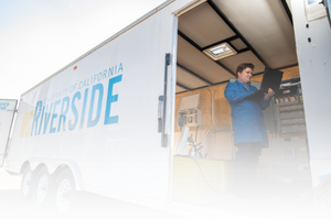 Electric Grid and Renewable Energy image Researcher in a blue lab coat working with engine testing equipment at CE-CERT.
