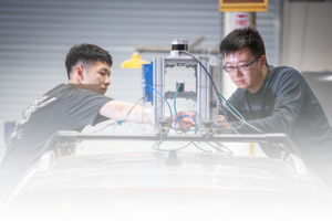 Sustainable Transportation and Community Impacts image Researcher in a blue lab coat working with engine testing equipment at CE-CERT.