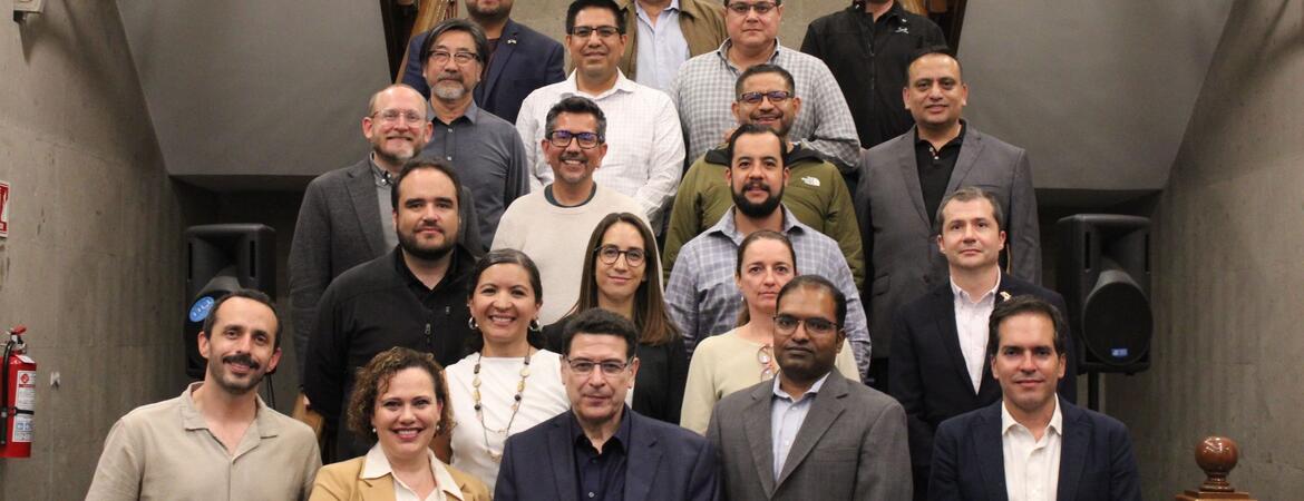 Twenty-two participants from the Binational Working Group on Zero-Emission Vehicles pose on a staircase at the Casa de la Universidad de California in Mexico City.