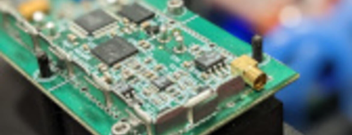 A detailed image of a circuit board with chips and other electronic components, mounted on a black structure.