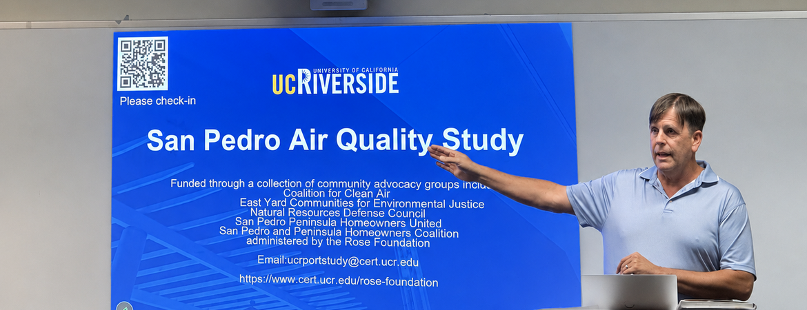 A CE-CERT researcher speaks at a community meeting in San Pedro, standing beside a projected presentation slide titled “San Pedro Air Quality Study.” The meeting was held at the Boys & Girls Club of the Los Angeles Harbor and focused on research examining the impact of ship emissions on local air quality.