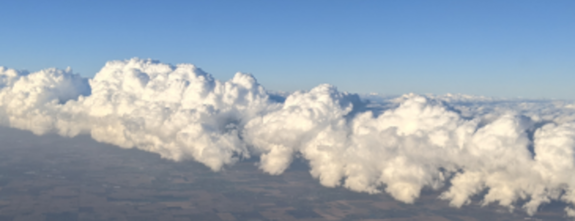 Aerial view of a landscape with a large roll of cumulus clouds stretching across the sky, photographed as part of atmospheric studies by Sarah Petters at UCR CE-CERT.
