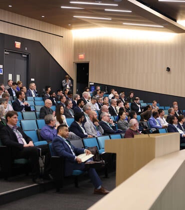 Audience members listen to a presentation in a large lecture hall during the Inaugural Hydrogen Engine Alliance – North America Conference, with keynote speaker Professor Thomas Koch presenting at the front.