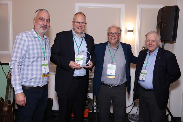 Georgios Karavalakis, Thomas Koch, André Boehman, and Wayne Miller pose together during the Inaugural H2EA-NA Conference banquet as Koch receives a thank-you gift for his keynote address.