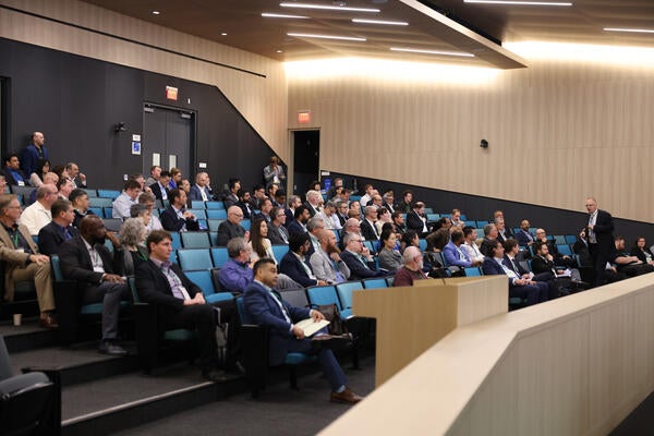 Audience members listen to a presentation in a large lecture hall during the Inaugural Hydrogen Engine Alliance – North America Conference, with keynote speaker Professor Thomas Koch presenting at the front.