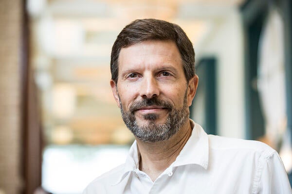 headshot of man with combover and facial hair in a white collared shirt