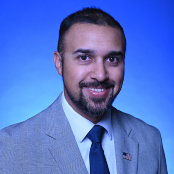 man with beard wearing suite smiling with blue background