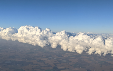 Aerial view of a landscape with a large roll of cumulus clouds stretching across the sky, photographed as part of atmospheric studies by Sarah Petters at UCR CE-CERT.