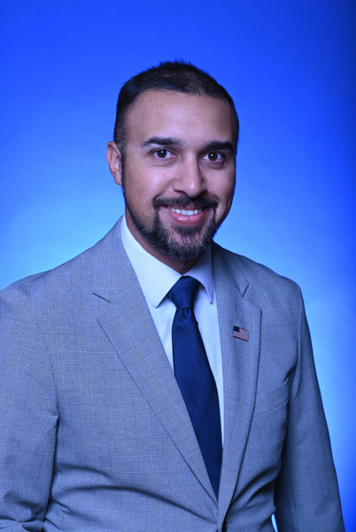 man with beard wearing suite smiling with blue background