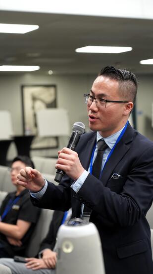 conference attendee with microphone in a suit asking questions