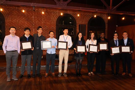 10 researchers standing together holding their awards from the conference for their outstanding contributions