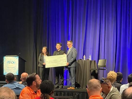 Ziyan Zhang holds a $5,000 scholarship check with two presenters onstage at the 2026 ITS California conference.